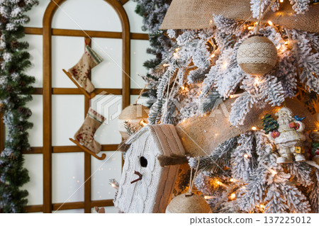 Christmas magic background. Beautiful decorated white xmas tree near huge window. Shining lights, baubles and garland. Winter holidays magic atmosphere. Modern design and decorations, copy space 137225012