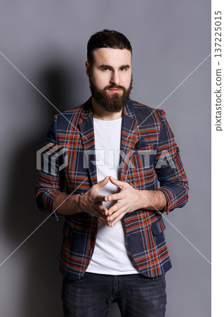 Bearded man with public speaker gesture. Fingers connected at fingertips, pose which imposes power and patience, gray studio background Bearded man with public speaker gesture. Fingers connected at fingertips, pose which imposes power and patience, gray studio background 137225015
