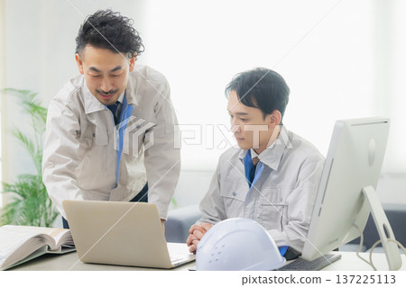 Engineers having a meeting while looking at documents at the office Engineers having a meeting while looking at documents at the office 137225113