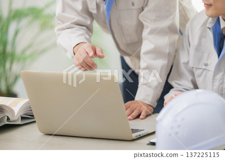 Engineers having a meeting while looking at documents at the office Engineers having a meeting while looking at documents at the office 137225115