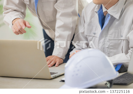 Engineers having a meeting while looking at documents at the office Engineers having a meeting while looking at documents at the office 137225116