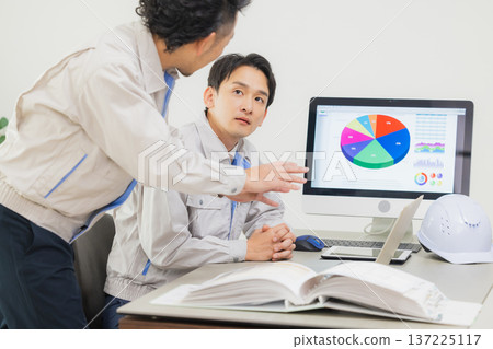 Engineers having a meeting while looking at documents at the office Engineers having a meeting while looking at documents at the office 137225117