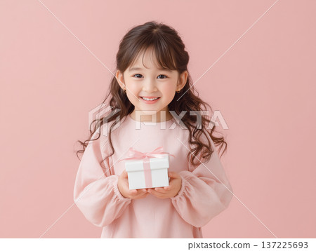 兒童模特兒雙手拿著禮物，在粉紅色背景下拍照 137225693