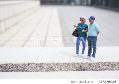 Miniature couple stands together on elevated outdoor platform 137226086
