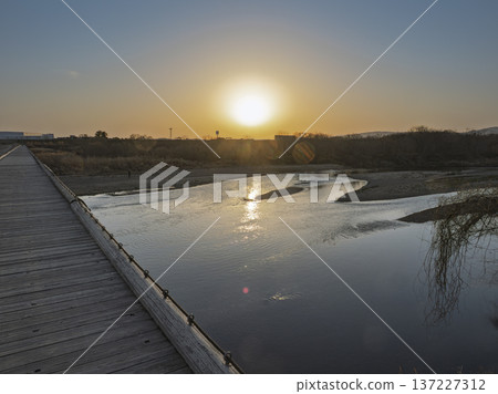 夕陽西下,一座浮橋沐浴在金色的餘暉中。木頭的溫暖與金色的靜謐交織在一起。 夕陽西下,一座浮橋沐浴在金色的餘暉中。木頭的溫暖與金色的靜謐交織在一起。 137227312