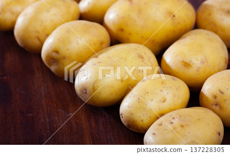 Raw fresh young potatoes at wooden table in home kitchen 137228305