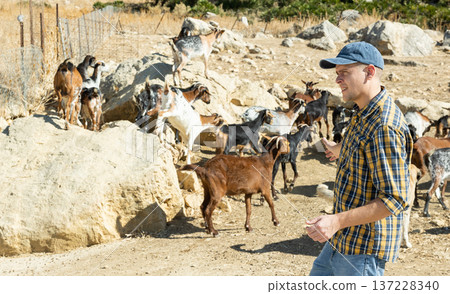 Portrait of happy successful man taking goats for walk on rocky area near farmhouse 137228340