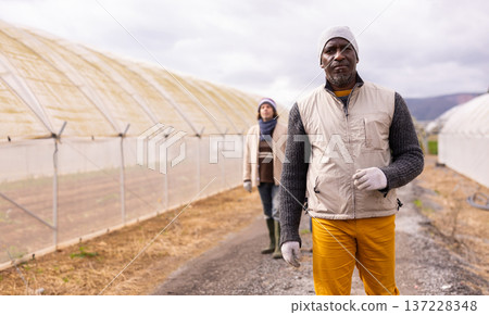 Adult male farmer standing in front of greenhouses Adult male farmer standing in front of greenhouses 137228348