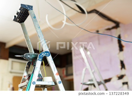 Interior of room being repaired with stepladder and wires Interior of room being repaired with stepladder and wires 137228349