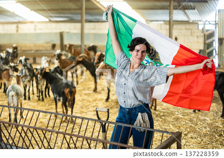 Happy Hispanic female farmer standing in goat shelter with flag of Mexico Happy Hispanic female farmer standing in goat shelter with flag of Mexico 137228359