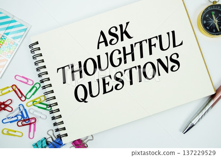 Ask Thoughtful Questions text message written on notepad with stationery flat lay on white background 137229529