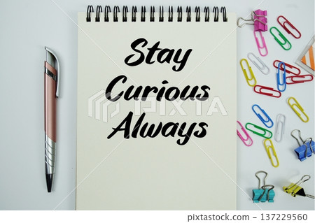 Stay Curious Always text message written on notepad with stationery flat lay on white background 137229560