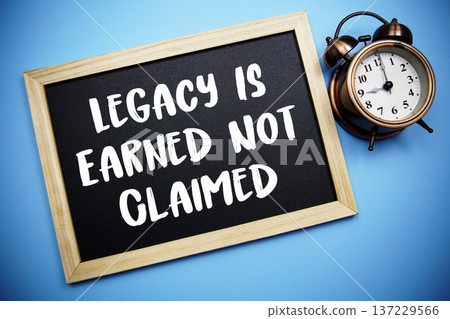 Legacy Is Earned Not Claimed text on Blackboard and alarm clock on blue background 137229566