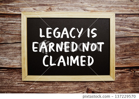 Legacy Is Earned Not Claimed text on Blackboard and alarm clock on wooden background 137229570