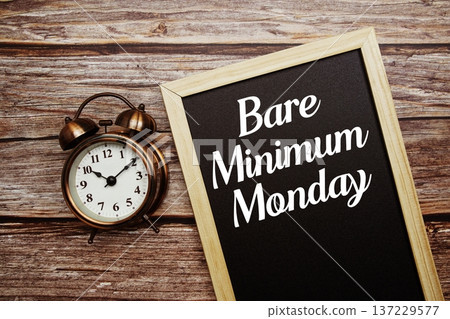 Bare Minimum Monday text on Blackboard and alarm clock on wooden background 137229577