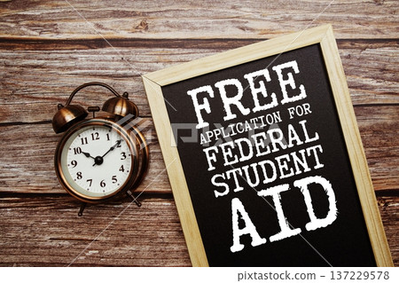 FAFSA Free Application for Federal Student Aid text on Blackboard and alarm clock on wooden background FAFSA Free Application for Federal Student Aid text on Blackboard and alarm clock on wooden background 137229578