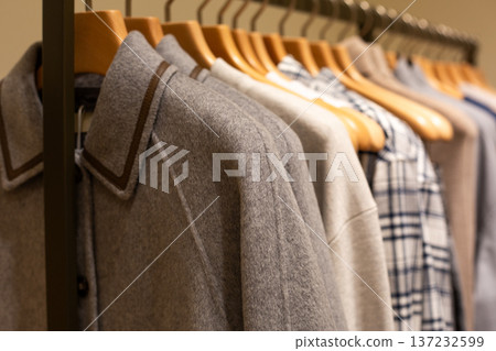 Coat on hanger in business casual store. Business attire for inclement weather. Business attire in premium clothing store. Expensive items on a hanger for luxury shopping spree Coat on hanger in business casual store. Business attire for inclement weather. Business attire in premium clothing store. Expensive items on a hanger for luxury shopping spree 137232599
