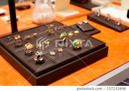 Shelf in jewelry store with set of rings and earrings. Pairs of jewelry in same style. Fine jewelry to highlight unified style. Buying jewelry for elegance and fashion. Jewelry set concept Shelf in jewelry store with set of rings and earrings. Pairs of jewelry in same style. Fine jewelry to highlight unified style. Buying jewelry for elegance and fashion. Jewelry set concept 137232606