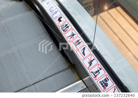 Warning signs on escalator illustrate prohibited actions including running, carrying large items, and using mobile phones, ensuring safety in public transportation environment 137232640