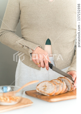 Woman's hands cutting bread for breakfast in the kitchen 137232898