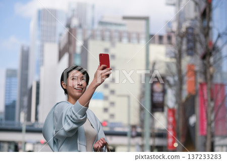 A woman taking pictures of the Ginza streets with her smartphone A woman taking pictures of the Ginza streets with her smartphone 137233283