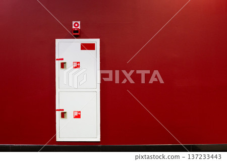 Fire boxes in red wall. Safety element hidden in the wall for timely fire extinguishing. Building safety thanks to water hose located in wall. Building fire concept with space for text 137233443
