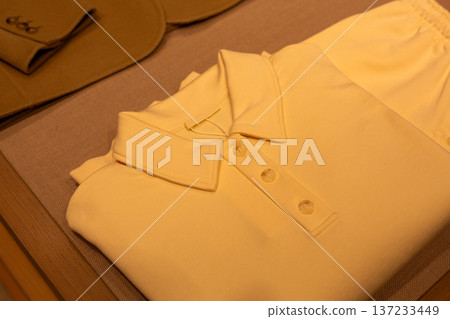 Neatly folded clothes on shelf with polo shirt. Order and perfectionism in everyday things. Clothes arranged on shelves. Complete order in the wardrobe. Clothes are wrinkle free and neatly folded 137233449