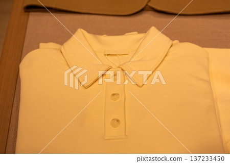 Yellow polo shirt neatly folded on shelf. Business style collared t shirt. Office attire option. Simple cropped t-shirt that mimics shirt. Business casual and neat attire Yellow polo shirt neatly folded on shelf. Business style collared t shirt. Office attire option. Simple cropped t-shirt that mimics shirt. Business casual and neat attire 137233450