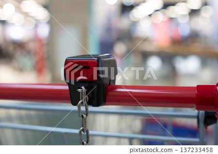 Coin operated lock on handle of shopping cart. Insert coin to release your cart. Return cart to supermarket to retrieve your coin. Locker provides cart control and security at grocery store Coin operated lock on handle of shopping cart. Insert coin to release your cart. Return cart to supermarket to retrieve your coin. Locker provides cart control and security at grocery store 137233458