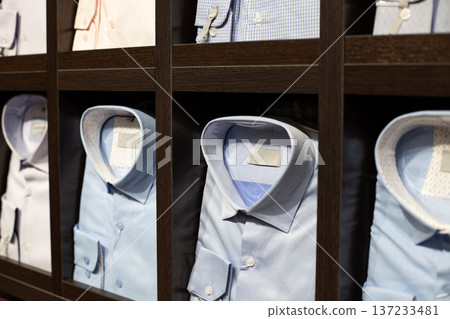 Light blue shirt as alternative to traditional white shirt. Shelf full of light blue shirts in various styles. Solid colors, checkered patterns and striped shirts. Buying new shirt for your look 137233481