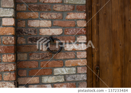 Iron doorknob for knocking on old house. Medieval door and knocker. Entrance to an ancient wooden door with vintage feel. Antique door in brick wall. Old metal brass knocker for door Iron doorknob for knocking on old house. Medieval door and knocker. Entrance to an ancient wooden door with vintage feel. Antique door in brick wall. Old metal brass knocker for door 137233484