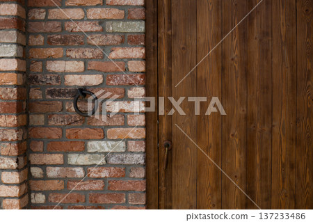 Closed antique door and round metal knocker. First methods of home security. Wooden door and brace to ensure familiar person knocks correctly. Secret knock for security. Stranger knocks incorrectly Closed antique door and round metal knocker. First methods of home security. Wooden door and brace to ensure familiar person knocks correctly. Secret knock for security. Stranger knocks incorrectly 137233486
