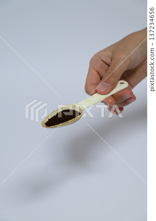 A person's hand scooping coffee powder with a spoon A person's hand scooping coffee powder with a spoon 137234656