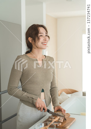 Woman cutting bread for breakfast in the kitchen 137234741