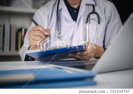 Doctor hand writing medical report clipboard hospital office desk. Physician checking patient chart diagnosis using pen. Healthcare professional insurance prescription concept. 137234747