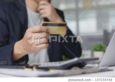 Close up man looking credit card calculating debt expense calculator. Serious person planning budget finance investment problem. Economic crisis money bankruptcy idea. Close up man looking credit card calculating debt expense calculator. Serious person planning budget finance investment problem. Economic crisis money bankruptcy idea. 137234748