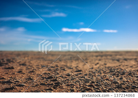 Cracked Soil Under Wide Blue Sky. Parched Terrain Showing Deep Cracks Stretching Towards Horizon Cracked Soil Under Wide Blue Sky. Parched Terrain Showing Deep Cracks Stretching Towards Horizon 137234868