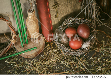 Ostara spring equinox celebration set with red eggs in nest, green candles and ancient book with brass key on hay background. Ostara spring equinox celebration set with red eggs in nest, green candles and ancient book with brass key on hay background. 137235079