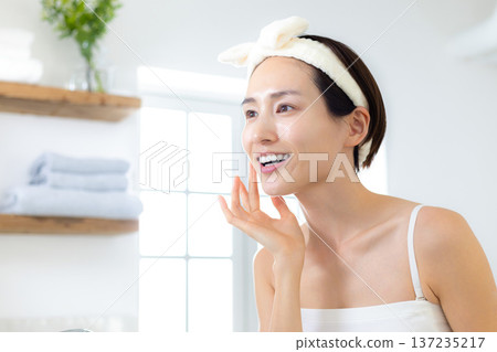 Beauty: A woman doing skin care in the bathroom Beauty: A woman doing skin care in the bathroom 137235217