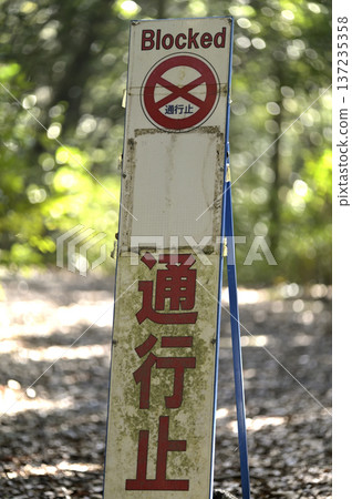 A moss-covered road-closure sign on a mountain path or abandoned road 137235358