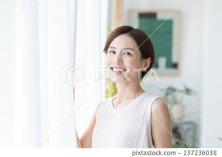 美麗的畫面:一位女子在窗邊微笑。 美麗的畫面:一位女子在窗邊微笑。 137236038