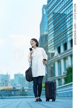 Woman with suitcase and smartphone in the city Woman with suitcase and smartphone in the city 137236194