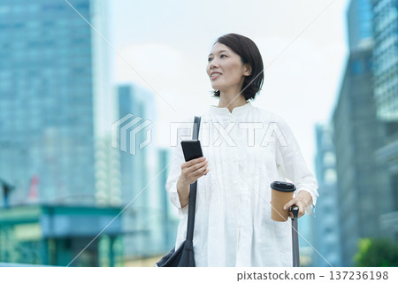 Woman with suitcase and smartphone in the city Woman with suitcase and smartphone in the city 137236198