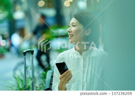 Woman with suitcase and smartphone in the city Woman with suitcase and smartphone in the city 137236209
