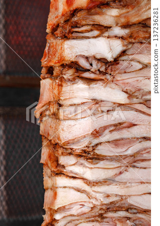Meat sitting on vertical spit and fried in electric oven, close-up, selective focus  137236281