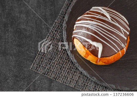 Chocolate icing cake on slate stone plate round, dark background, selective focus Chocolate icing cake on slate stone plate round, dark background, selective focus 137236606