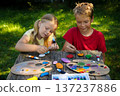 Young artists create colorful scenes on smooth pebbles, crafting unique handmade gifts for loved ones. 137237886