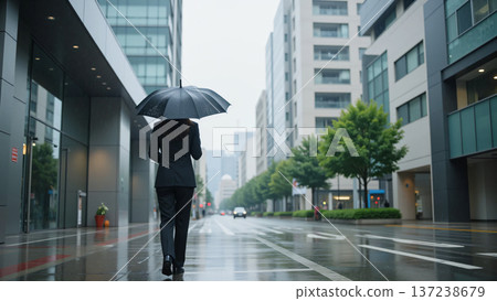 下雨天，一位身穿西裝的女士撐著傘行走。 137238679