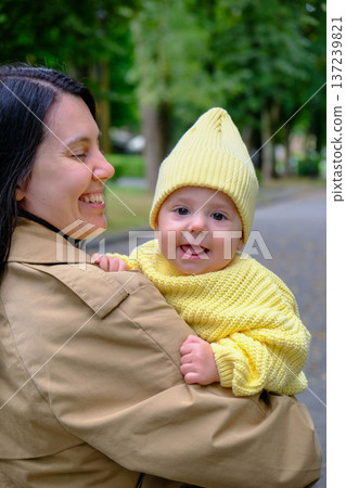 Mother Holding Baby in Yellow Outfit at Park 137239821