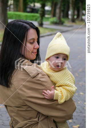 Mother Holding Baby in Yellow Outfit at Park Mother Holding Baby in Yellow Outfit at Park 137239825